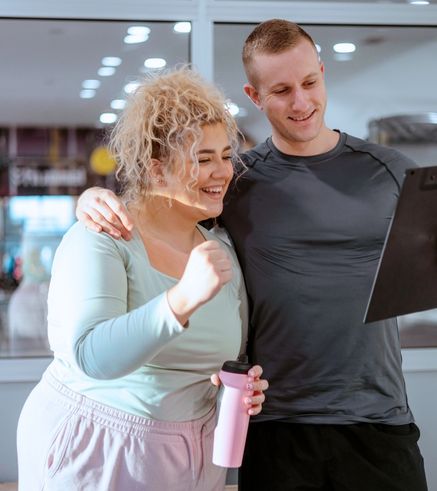 Personal trainer coaching a smiling woman with a fitness plan at Everyone Fitness gym